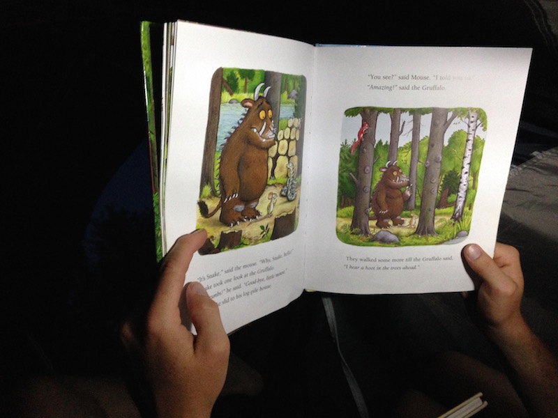 family reading in tent gruffalo book